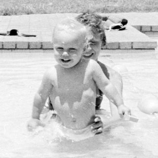 Children playing in backyard swimming pool.