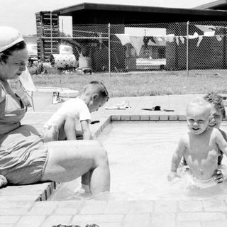 Children playing in backyard swimming pool.