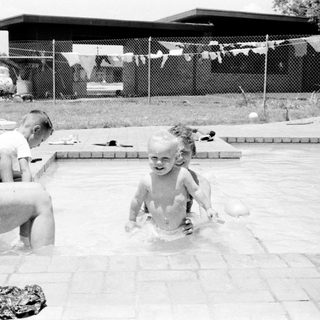 Children playing in backyard swimming pool.