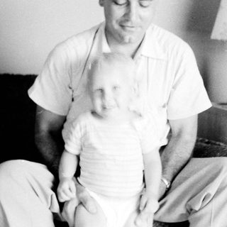 Man holding and comforting a young child indoors.