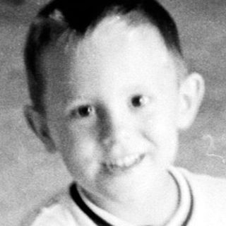 Young boy smiling indoors in playroom setting.