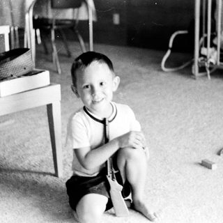 Young boy smiling indoors in playroom setting.