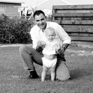 Man kneeling with young child outdoors.