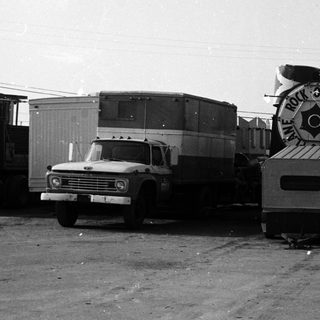Vintage trucks with large industrial reels labeled "Ray Plant Oil."