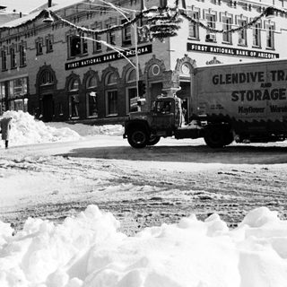 Snow-covered city street with truck clearing snow.