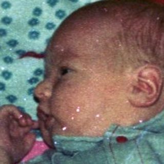 Baby sleeping on colorful patchwork blanket.