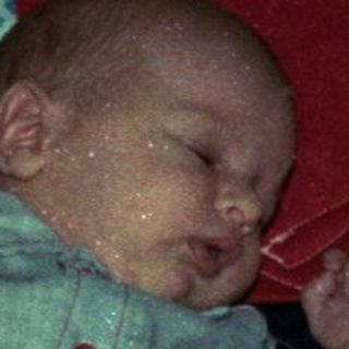 Baby sleeping on colorful patchwork quilt.