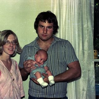 Family portrait with parents holding newborn baby.