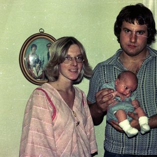 Family portrait with parents holding newborn baby.