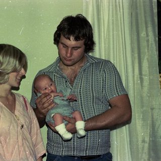 Family portrait with parents holding newborn indoors.