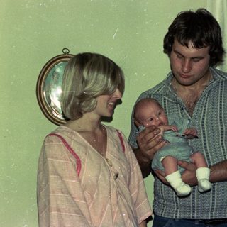 Family portrait with parents holding newborn indoors.