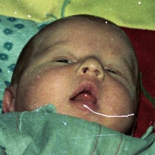 Newborn baby wrapped in colorful cloth.