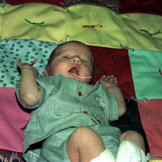 Newborn baby wrapped in colorful cloth.