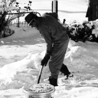 Person shoveling snow-covered residential driveway.