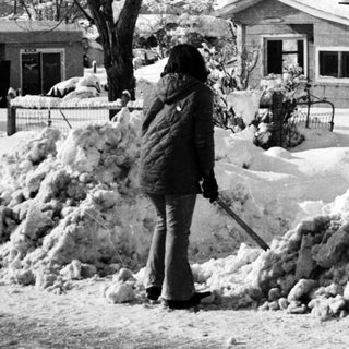 People shoveling heavy snow in a residential area.