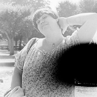 Person posing with arm stretched upward outdoors.