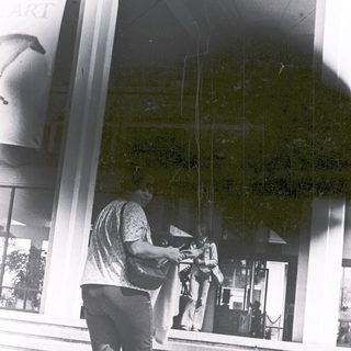 Person holding umbrella outside modern building entrance.