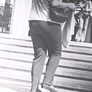 Person holding umbrella outside modern building entrance.