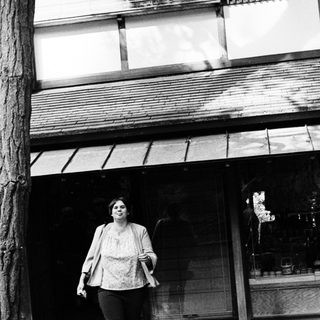 Woman walking outside near a storefront.
