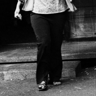 Woman walking outside near a storefront.