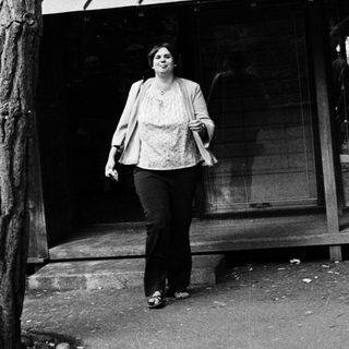 Woman walking outside near a storefront.