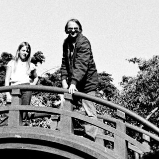 People posing on a curved wooden bridge in a park.