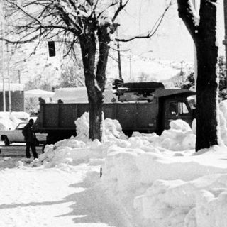 Heavy snowfall disrupts urban area with cleared path.