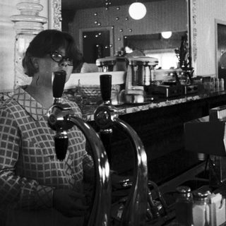 Woman drinking coffee at vintage bar counter.