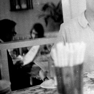 Woman sitting at table with drink and meal.