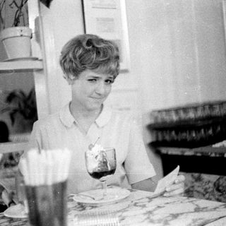 Woman sitting at table with drink and meal.