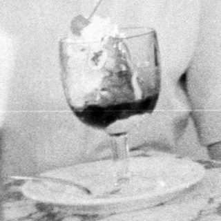 Woman sitting at table with drink and meal.
