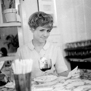 Woman sitting at table with drink and meal.