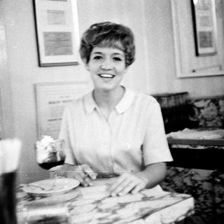 Woman smiling while serving food in kitchen.