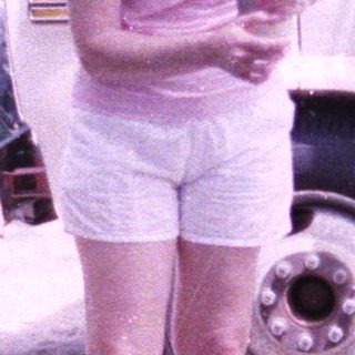 A woman and young child walking outdoors near parked vehicles.