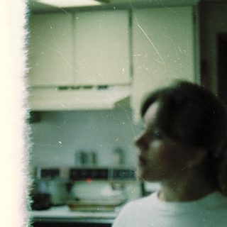 Blurred indoor kitchen scene with person wearing white shirt.