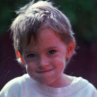 A smiling child with wet hair and droplets.