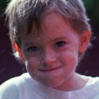 A smiling child with wet hair and droplets.