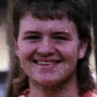 Person smiling outdoors near a generator.