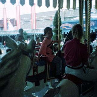 Classic carousel with seated riders enjoying amusement park.