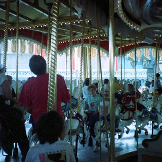 Classic indoor carousel with people riding horses.