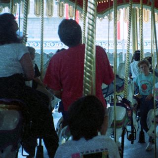 Classic indoor carousel with people riding horses.