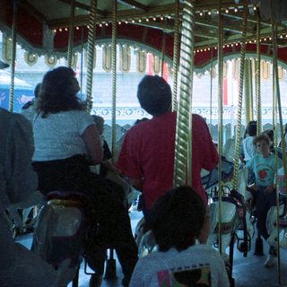 Classic indoor carousel with people riding horses.