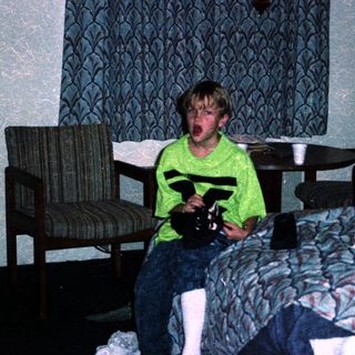 Boy in hotel room holding toy gun.