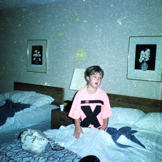 Child in pink shirt with X on bed.