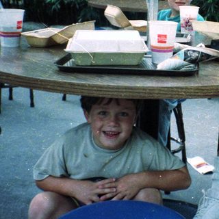 Family enjoying fast food outdoors at picnic tables.