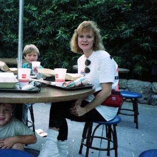 Family enjoying fast food outdoors at picnic tables.