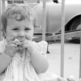 Young girl eating with hands in vintage outdoor setting.