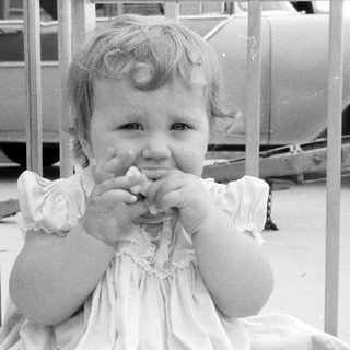 Young girl eating with hands in vintage outdoor setting.