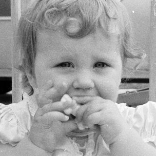 Young girl eating with hands in vintage outdoor setting.