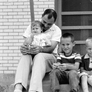 Family portrait with father and four children on porch.